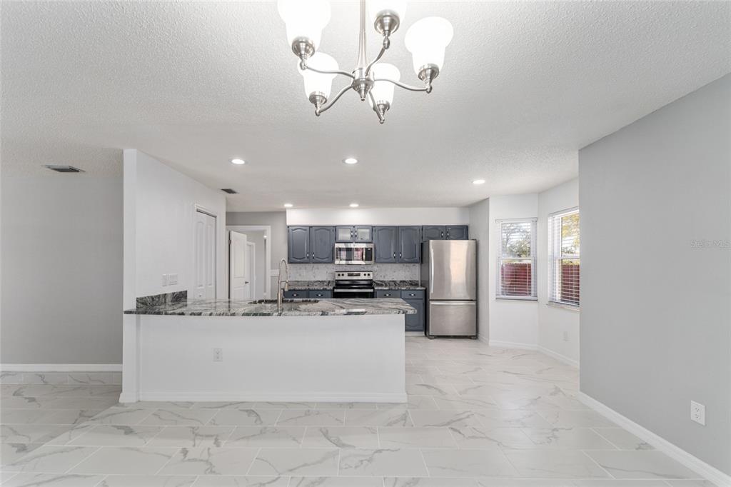 5041 Northeast 4th Street Ocala, FL 34470 - Photo 21 of 70 a kitchen with stainless steel appliances kitchen island granite countertop a refrigerator a stove a microwave oven with a dining table and chairs