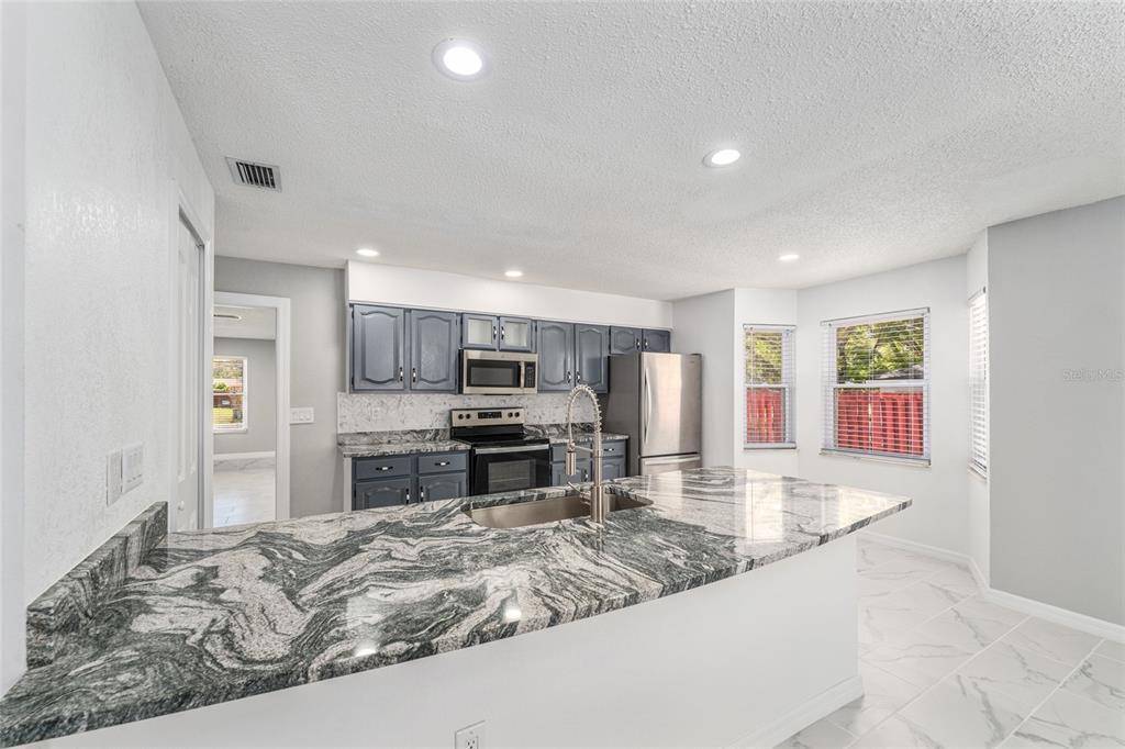 5041 Northeast 4th Street Ocala, FL 34470 - Photo 23 of 70 a large kitchen with kitchen island granite countertop a large counter top stainless steel appliances and cabinets