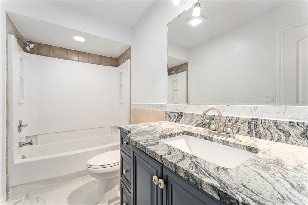 5041 Northeast 4th Street Ocala, FL 34470 - Photo 41 of 70 a bathroom with a granite countertop sink a toilet and shower