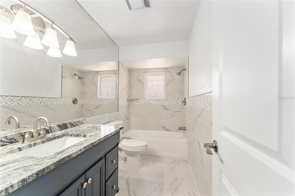 5041 Northeast 4th Street Ocala, FL 34470 - Photo 46 of 70 a bathroom with a granite countertop sink a toilet and shower