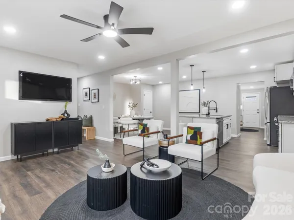 a living room with furniture a flat screen tv and kitchen view