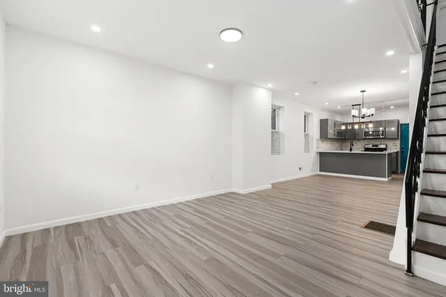 a view of an empty room with wooden floor and stairs
