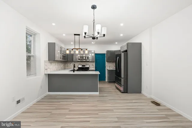 a kitchen with stainless steel appliances kitchen island granite countertop a refrigerator a stove a microwave oven a sink with wooden floor and cabinets
