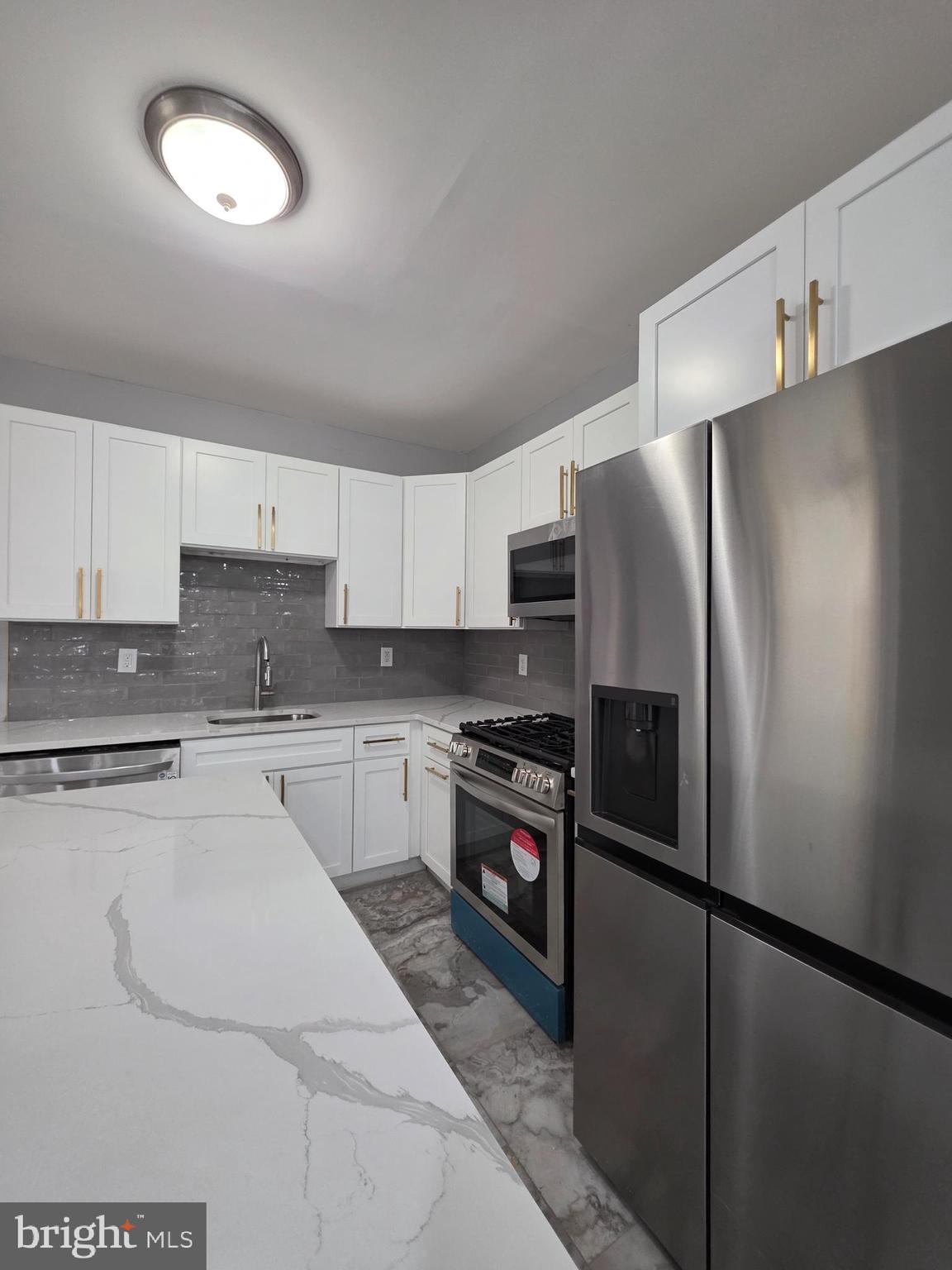 6026 Irving Street Philadelphia, PA 19139 - Photo 8 of 30 a kitchen with granite countertop a refrigerator and a stove top oven