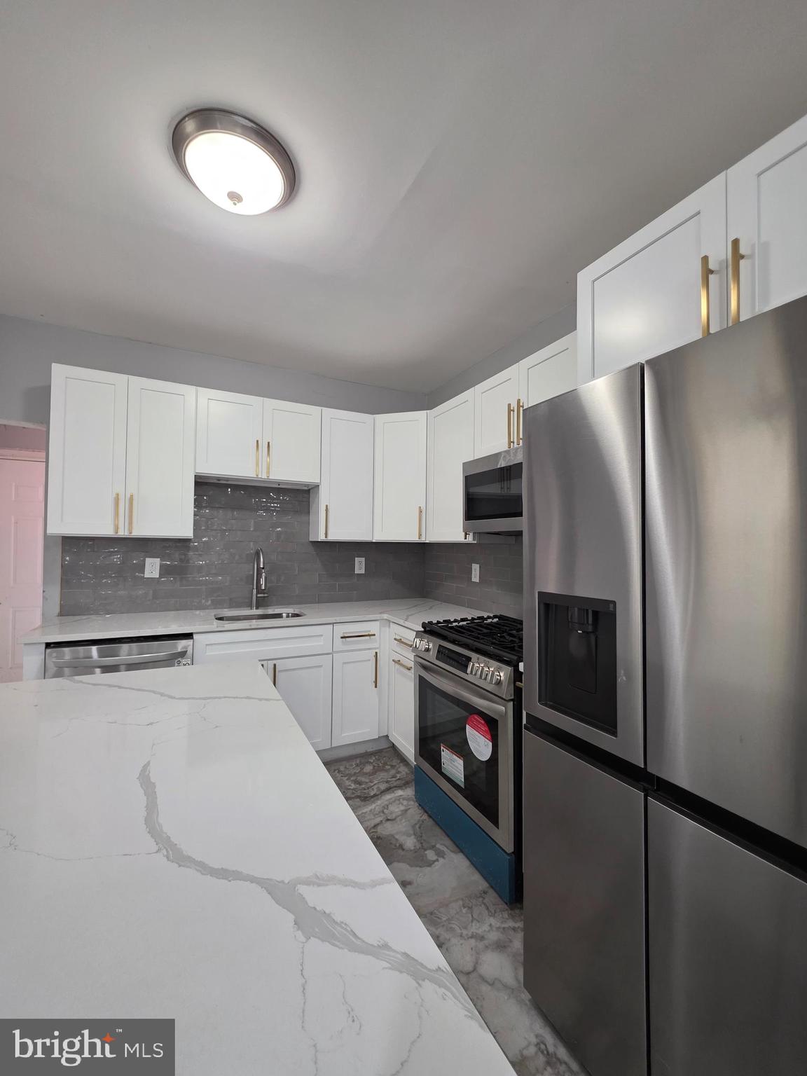 6026 Irving Street Philadelphia, PA 19139 - Photo 9 of 30 a kitchen with stainless steel appliances granite countertop a refrigerator a stove a sink and a microwave