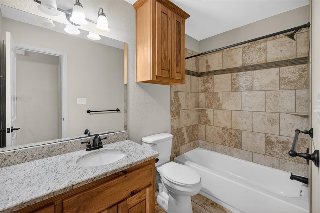 505 East 5th Street Springtown, TX 76082 - Photo 29 of 39 a bathroom with a granite countertop sink a toilet and bathtub