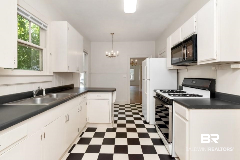 112 South Fulton Street Mobile, AL 36606 - Photo 18 of 35 Kitchen with white cabinets, a chandelier, sink, white gas range oven, and pendant lighting