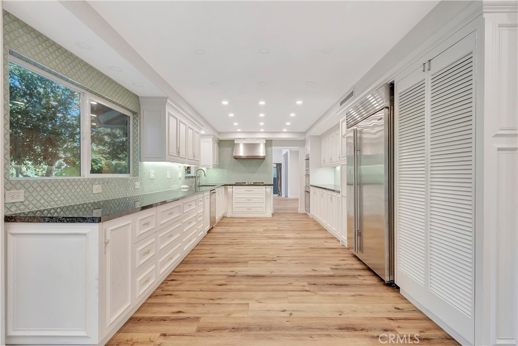 119 Bell Cyn Road Bell Canyon, CA 91307 - Photo 3 of 18 a large white kitchen with granite countertop lots of counter space wooden floor and stainless steel appliances