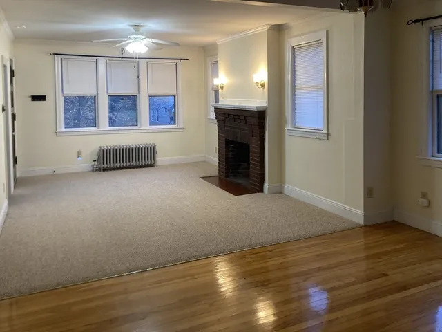 an empty room with wooden floor fireplace and windows