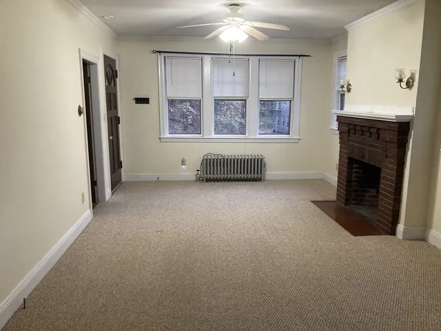 an empty room with windows and fireplace