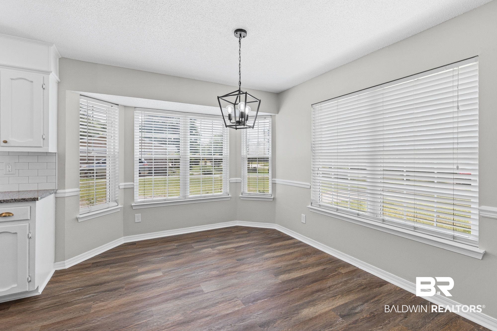 1301 Repoll Road Mobile, AL 36695 - Photo 8 of 21 Dining area featuring wood-finish flooring, a contemporary geometric chandelier, and a bay window with multiple panes