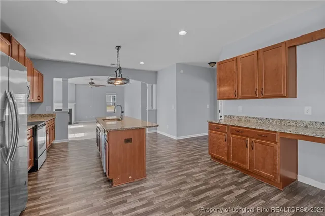 a kitchen with stainless steel appliances granite countertop a sink stove and wooden cabinets