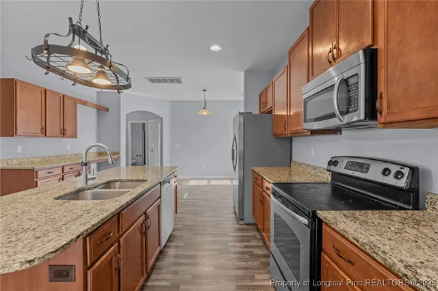 a kitchen with stainless steel appliances granite countertop a sink stove and refrigerator
