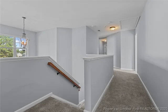 a view of a hallway to an empty room with wooden floor and a window
