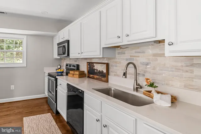 a kitchen with stainless steel appliances granite countertop a sink and white cabinets