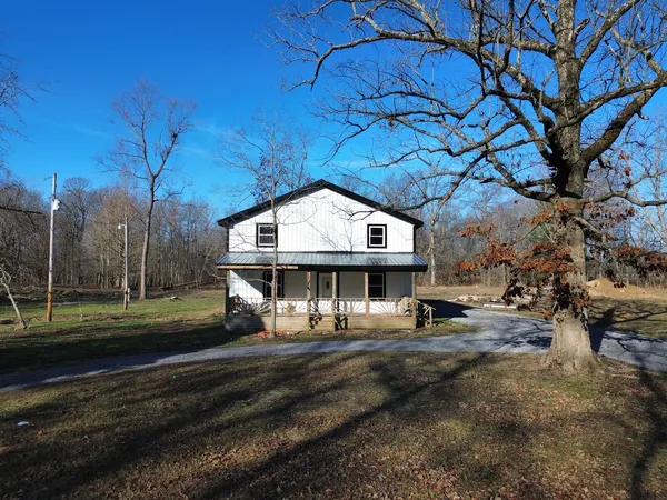 a view of big house with a big yard and large trees