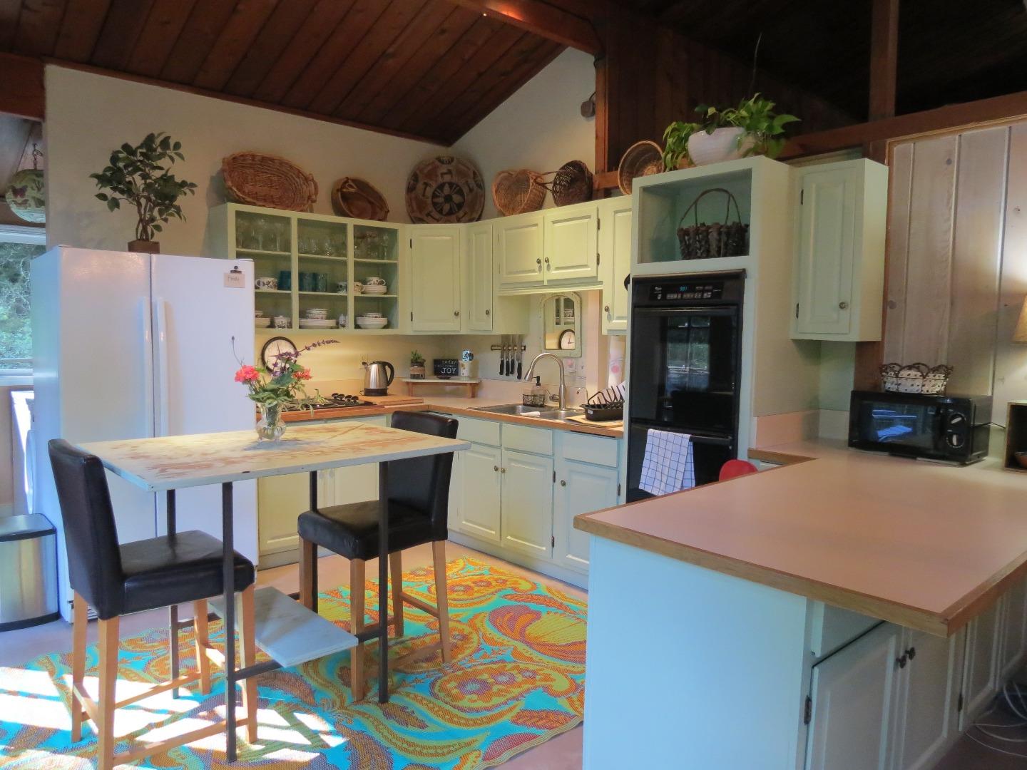 66 Wurr Road Loma Mar, CA 94021 - Photo 4 of 34 a kitchen with stainless steel appliances kitchen island granite countertop a table chairs and a refrigerator