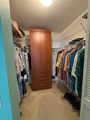 a view of walk in closet with clothes and shoes