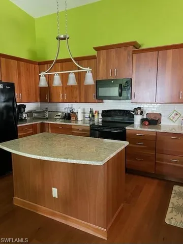 a view of a kitchen with kitchen island a stove a sink and a microwave