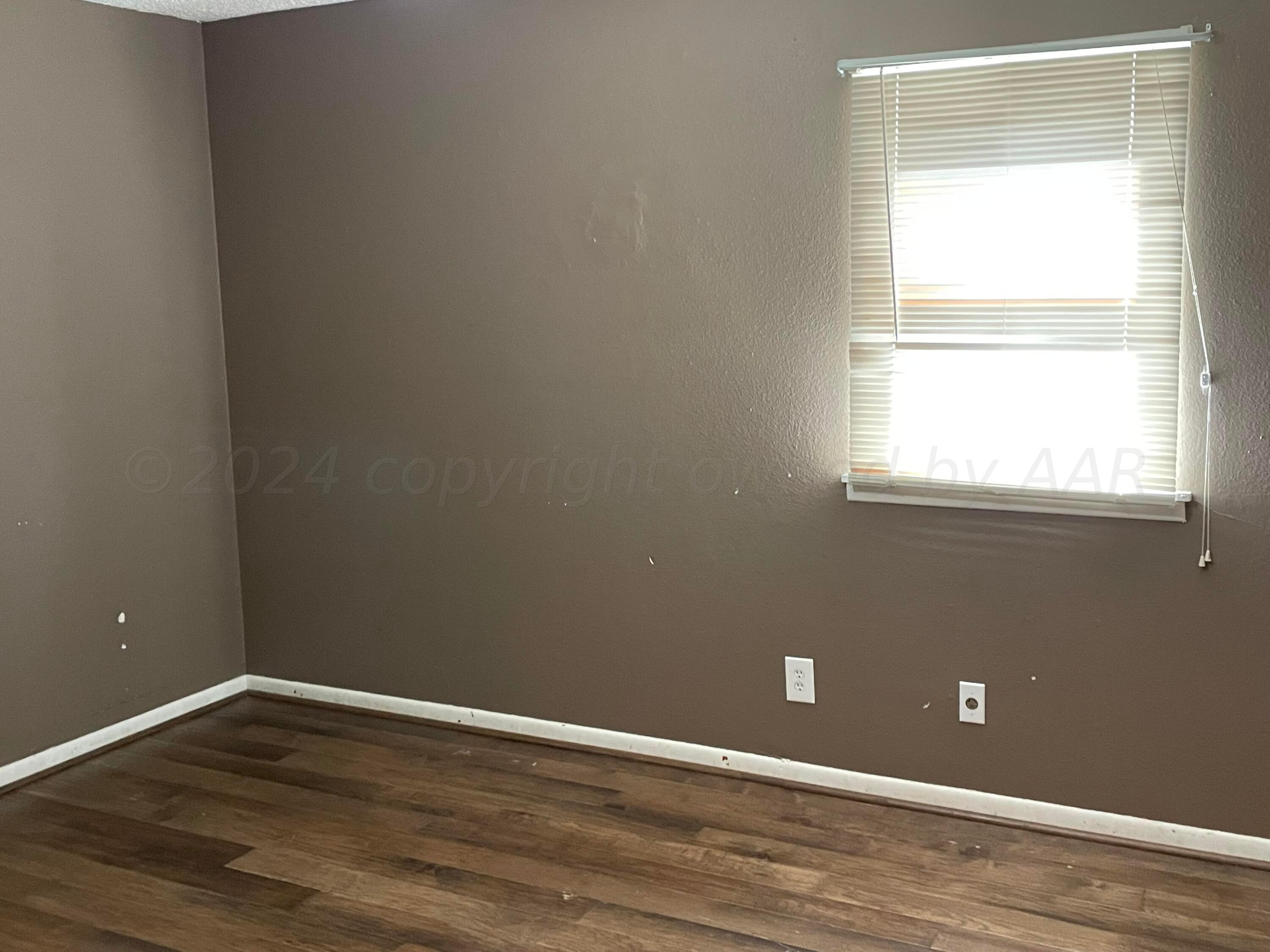 2014 South Drake Street Perryton, TX 79070 - Photo 6 of 10 a view of an empty room with wooden floor and a window