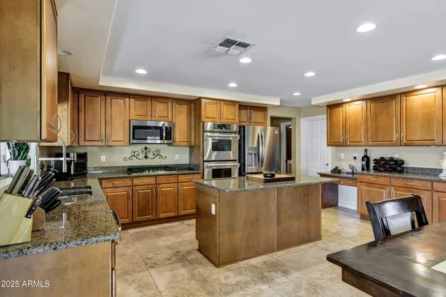 a kitchen with kitchen island granite countertop a table chairs sink and cabinets