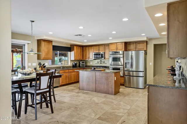 a kitchen with stainless steel appliances granite countertop a stove top oven a sink dishwasher a dining table and chairs with wooden floor