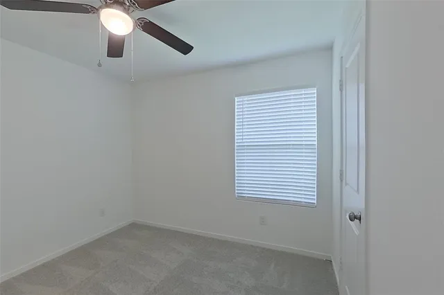 an empty room with a window and a fan