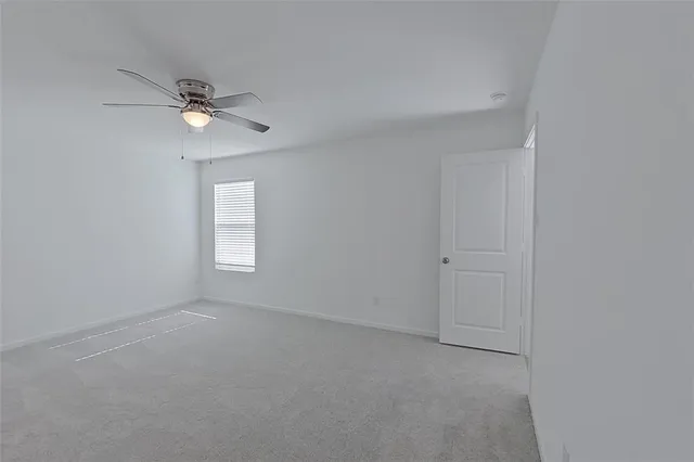 an empty room with a window and ceiling fan