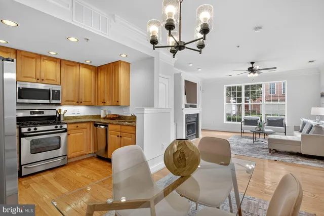 a kitchen with stainless steel appliances granite countertop a stove a refrigerator a kitchen island a dining table and chairs with wooden floor