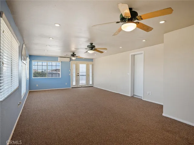 an empty room with wooden floor closet fan and windows