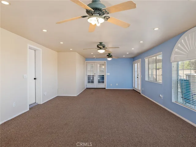 an empty room with wooden floor ceiling fan and windows