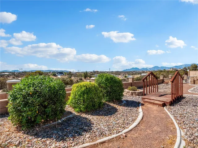 a view of a livingroom with a fireplace a ceiling fan and windows