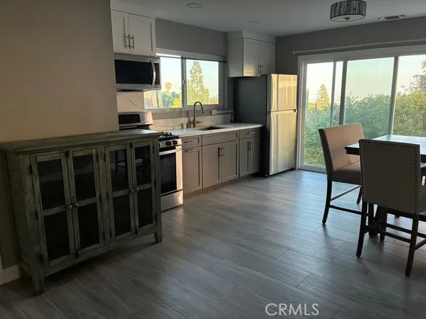 a kitchen with stainless steel appliances a stove top oven a sink a dining table and chairs