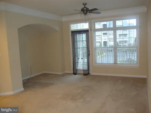 an empty room with chandelier fan and windows