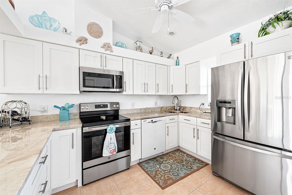 4260 Placida Road, Unit 12C Englewood, FL 34224 - Photo 19 of 57 a kitchen with stainless steel appliances granite countertop a refrigerator stove a sink and white cabinets