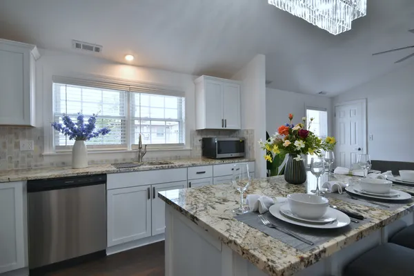 a kitchen with stainless steel appliances granite countertop a sink dishwasher a stove a refrigerator with a dining table and chairs