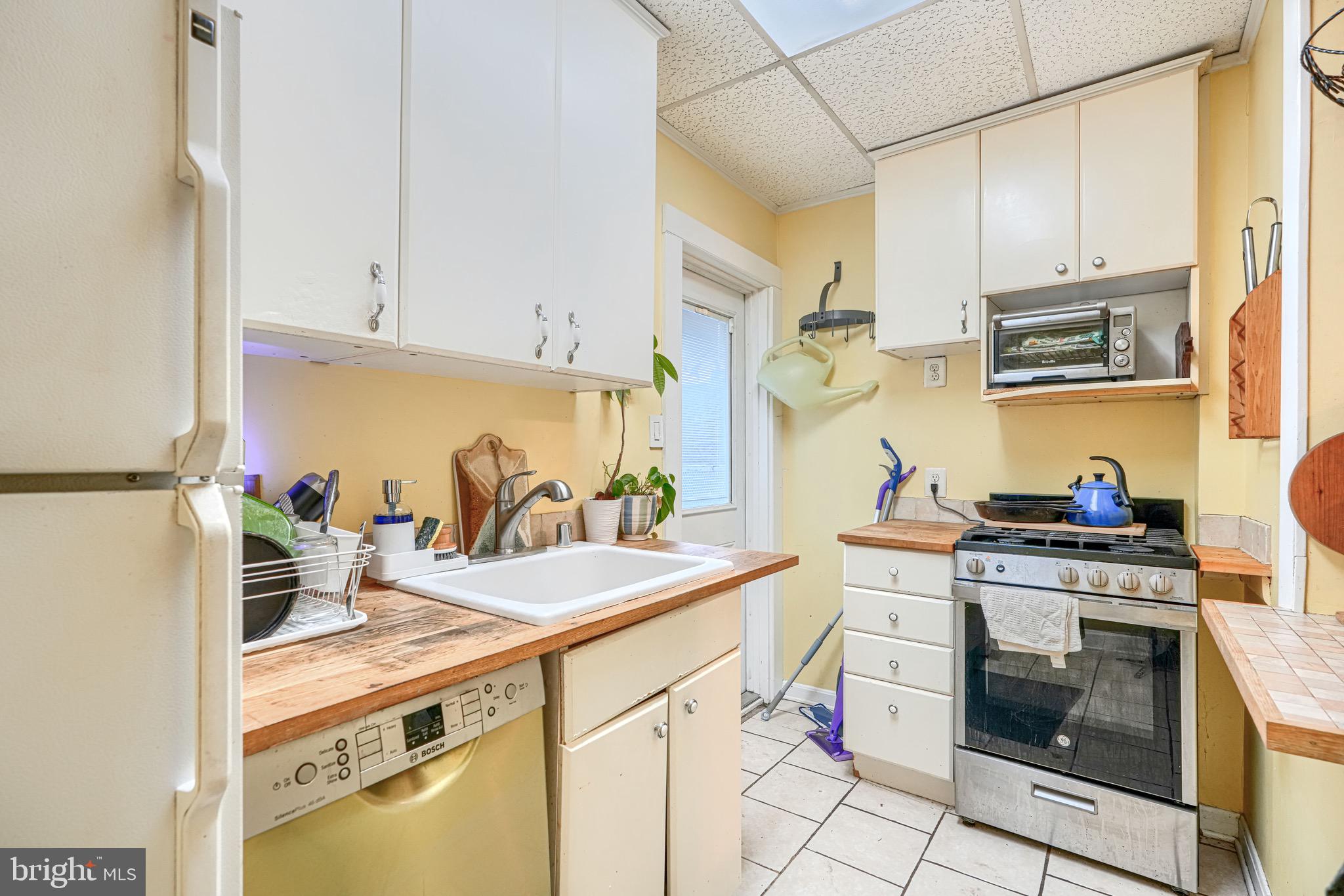 512 South Curley Street Baltimore, MD 21224 - Photo 15 of 29 a kitchen with kitchen island a stove a sink dishwasher and white cabinets with wooden floor