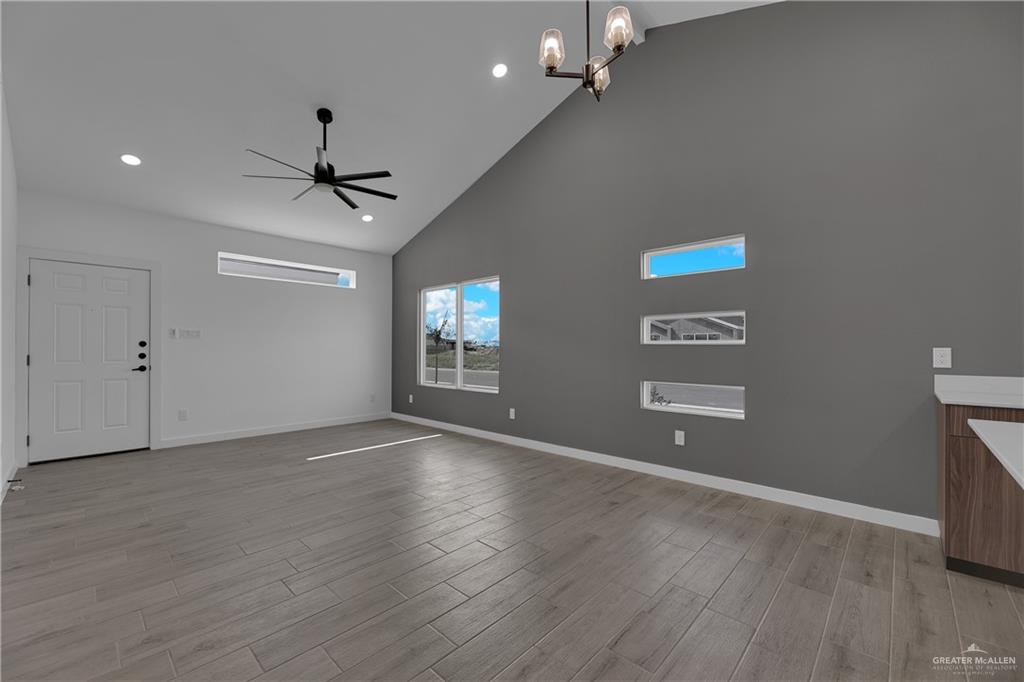 2509 Mockingbird Road, Unit B Weslaco, TX 78596 - Photo 5 of 11 Unfurnished living room featuring light hardwood / wood-style flooring, ceiling fan with notable chandelier, and high vaulted ceiling