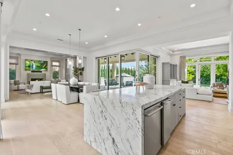 a large kitchen with kitchen island a stove a sink a refrigerator and white cabinets with wooden floor