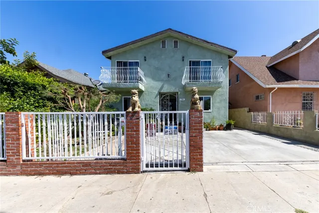 a view of a house with a small yard and wooden fence
