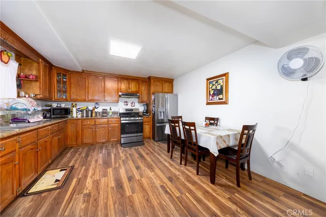 a kitchen with stainless steel appliances wooden floor dining table and chairs