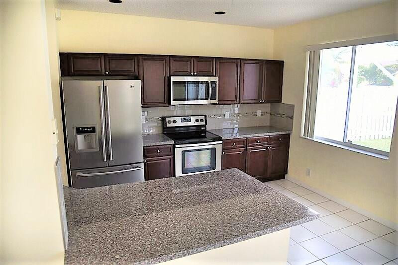 552 Talavera Road Weston, FL 33326 - Photo 8 of 16 a kitchen with stainless steel appliances granite countertop a refrigerator stove and microwave
