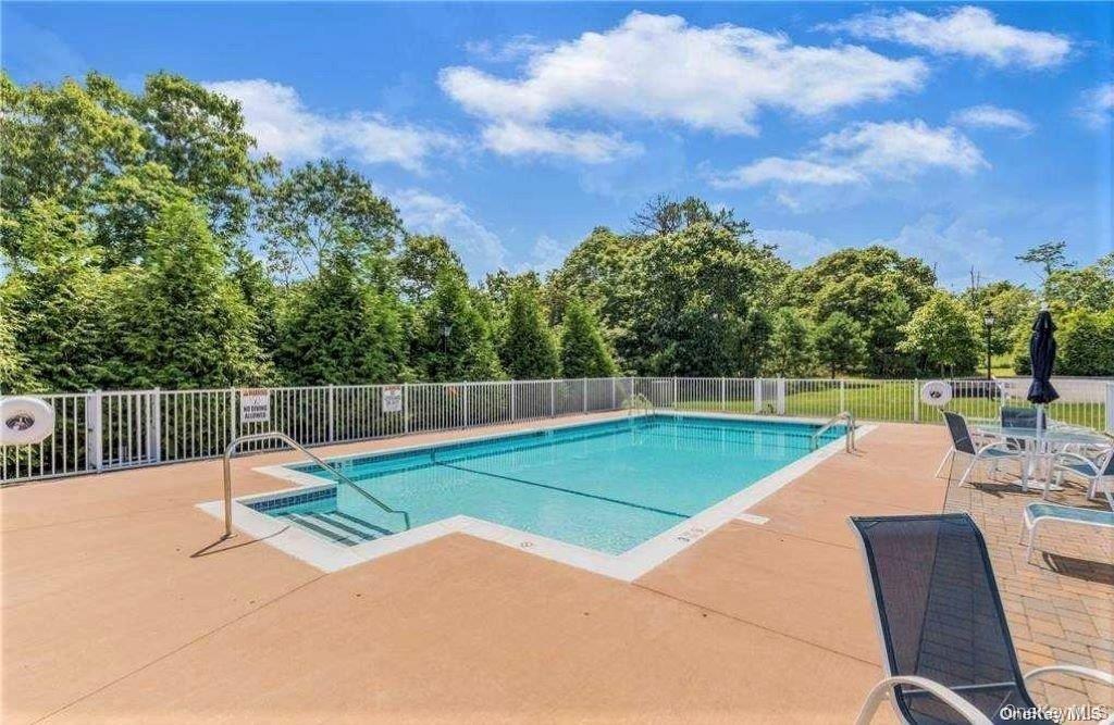 20 Canoe Place Road, Unit 8 Hampton Bays, NY 11946 - Photo 18 of 18 a view of a backyard with swimming pool and wooden fence