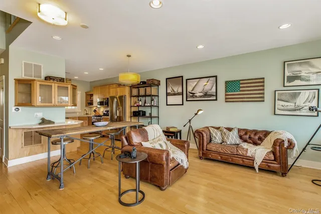 a living room with furniture kitchen view and a wooden floor