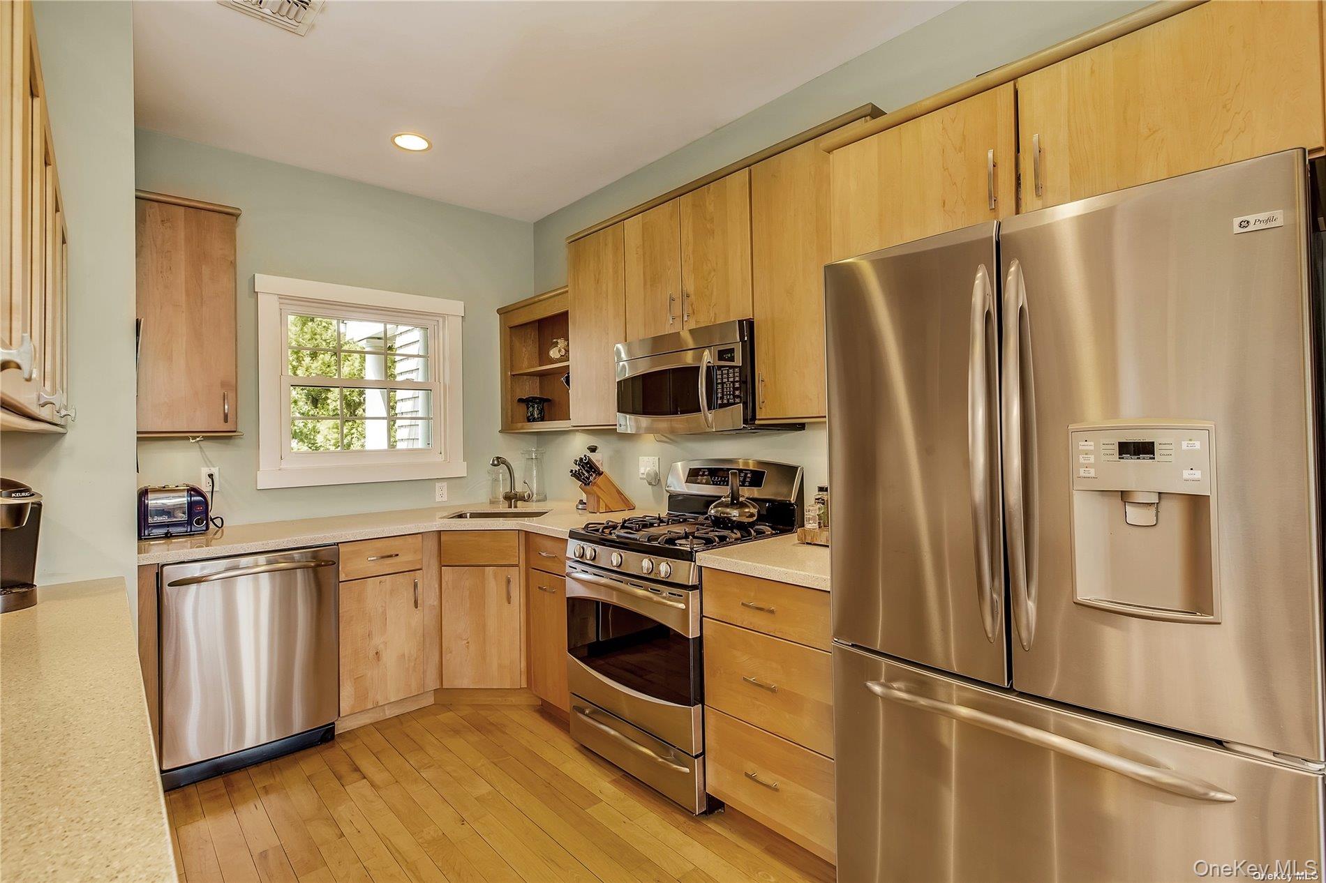 20 Canoe Place Road, Unit 8 Hampton Bays, NY 11946 - Photo 6 of 18 a kitchen with stainless steel appliances a refrigerator sink and microwave