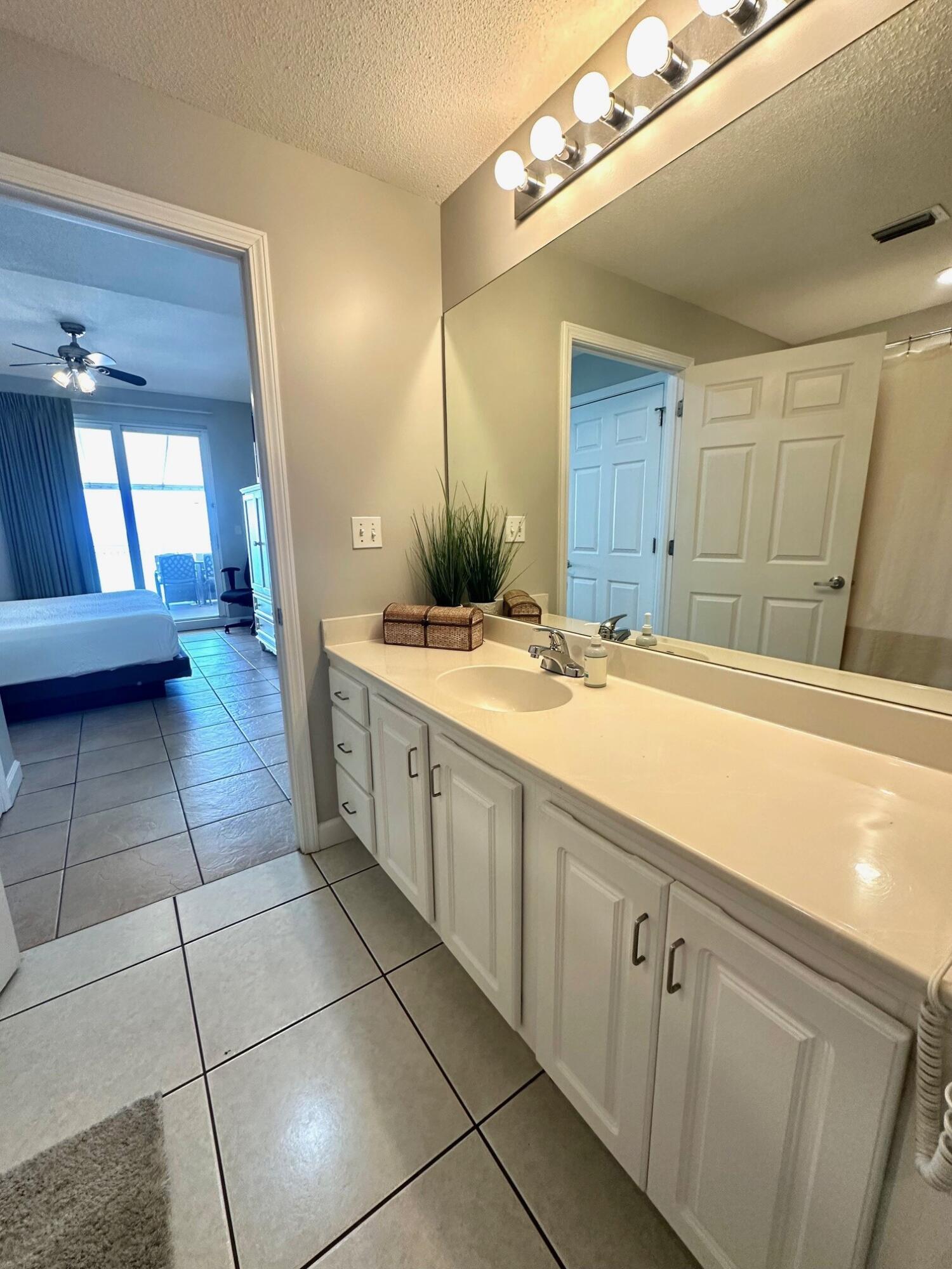 12011 Front Beach Road, Unit 103B Panama City Beach, FL 32407 - Photo 11 of 38 a bathroom with a sink a mirror and a shower