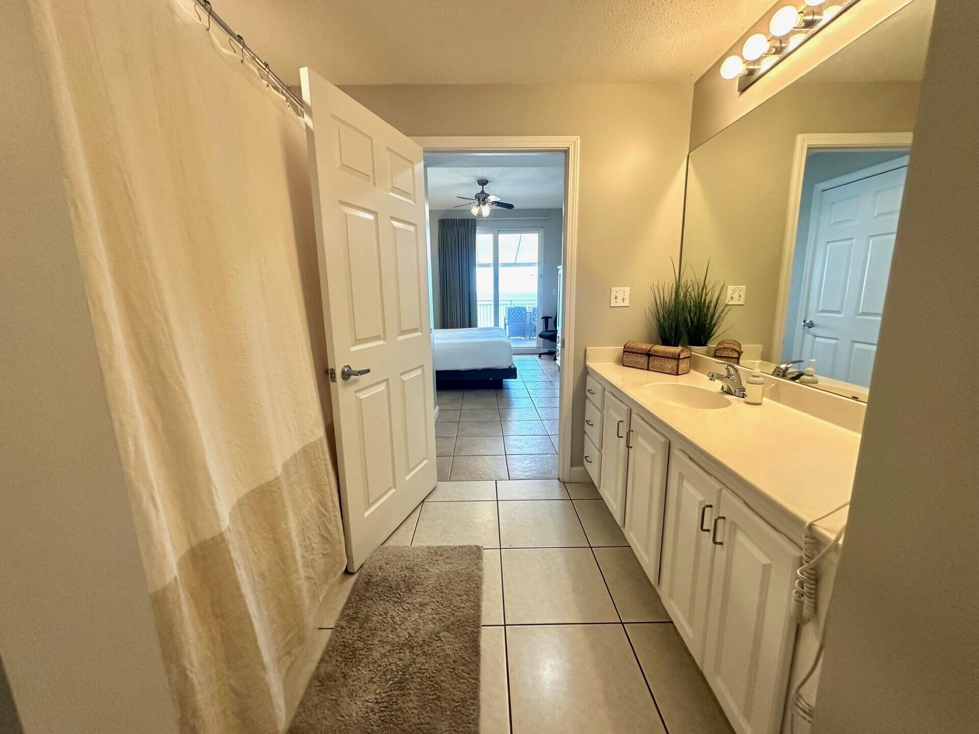 12011 Front Beach Road, Unit 103B Panama City Beach, FL 32407 - Photo 12 of 38 a bathroom with a sink a toilet a mirror and vanity