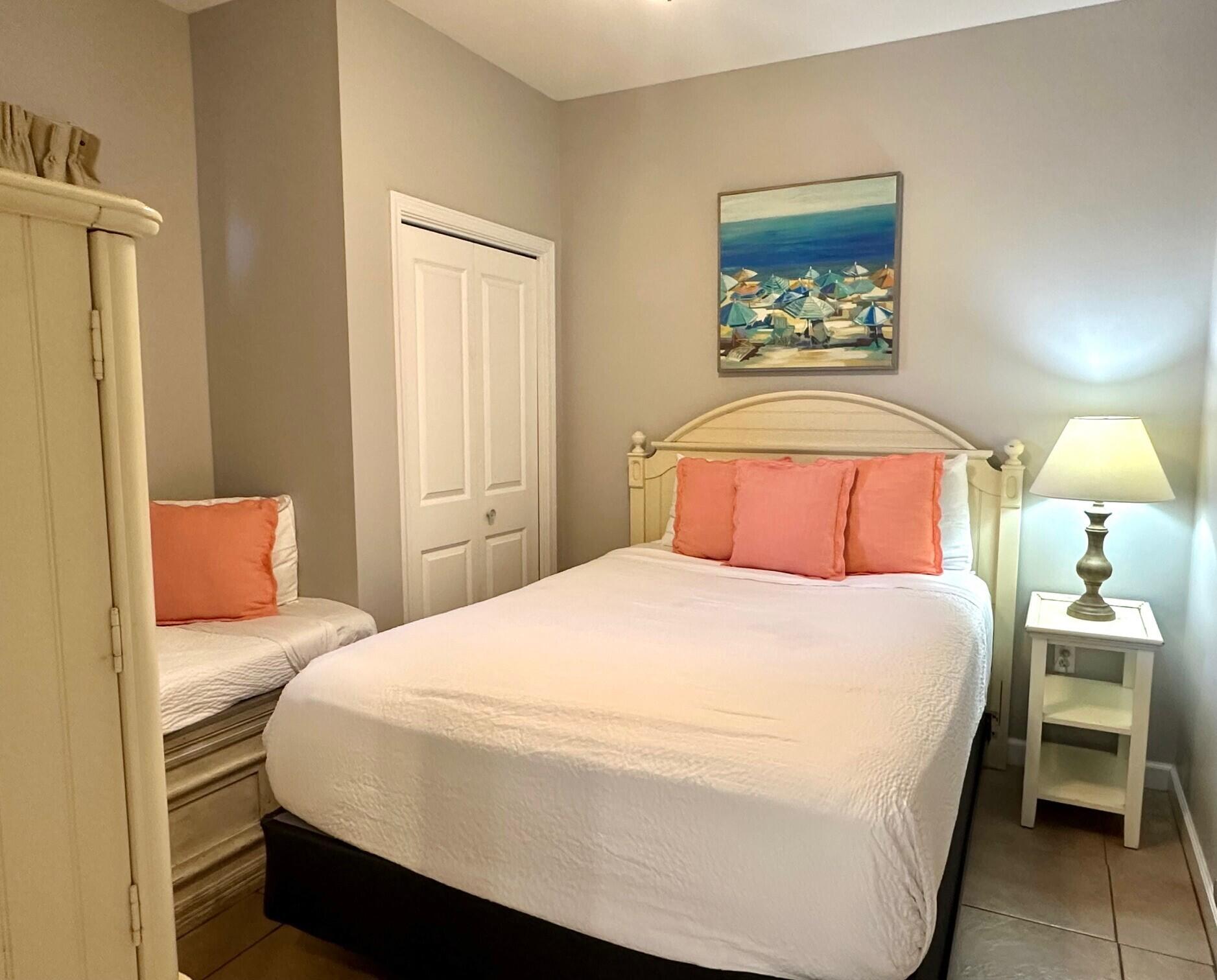 12011 Front Beach Road, Unit 103B Panama City Beach, FL 32407 - Photo 14 of 38 a bedroom with a bed and a lamp on dresser