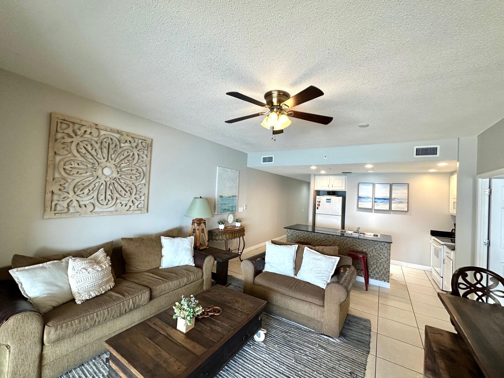 12011 Front Beach Road, Unit 103B Panama City Beach, FL 32407 - Photo 3 of 38 a living room with furniture a rug and a chandelier