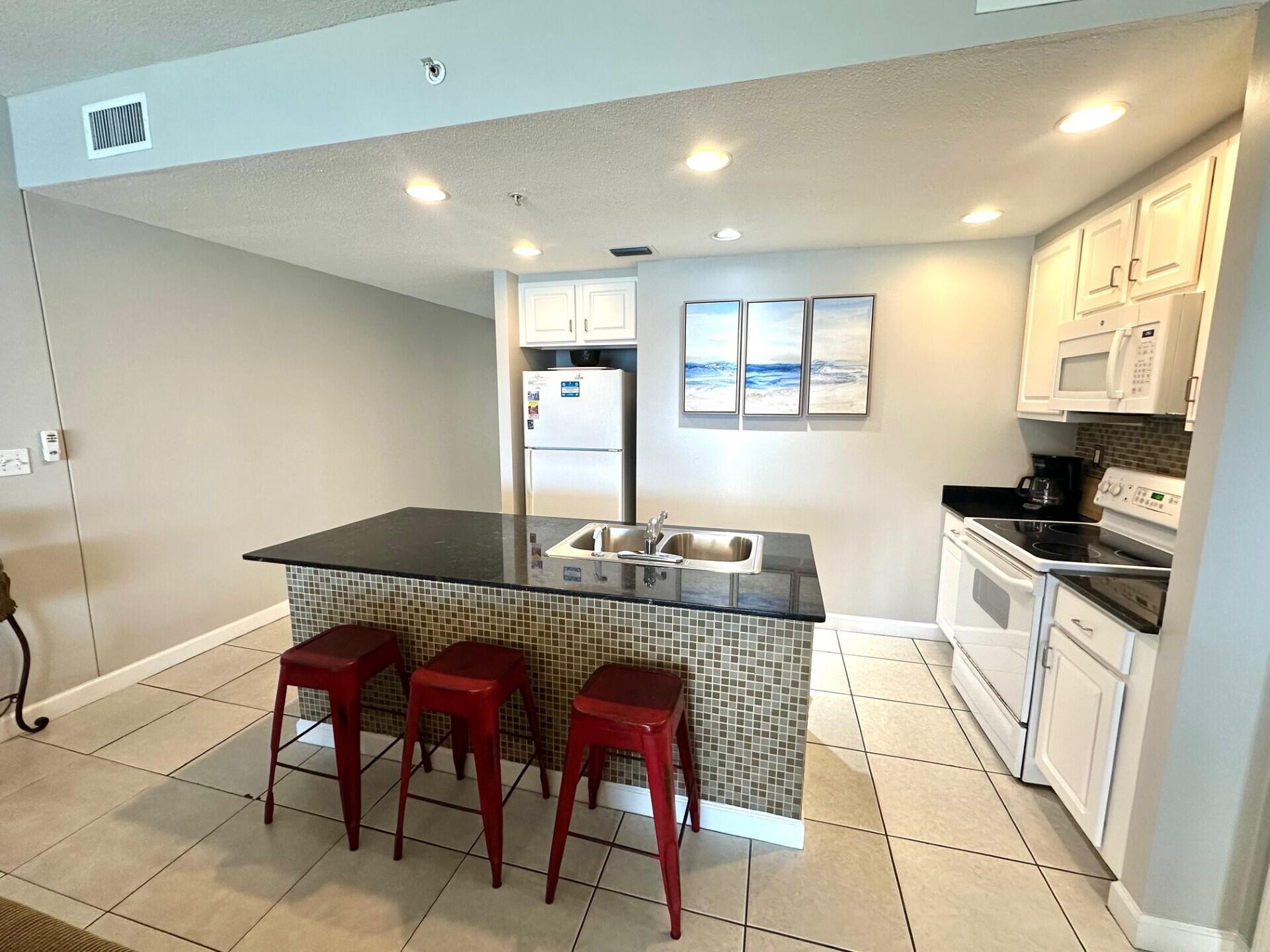 12011 Front Beach Road, Unit 103B Panama City Beach, FL 32407 - Photo 6 of 38 a kitchen with stainless steel appliances granite countertop a sink and a refrigerator